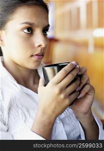 Close-up of a teenage girl holding a cup of coffee