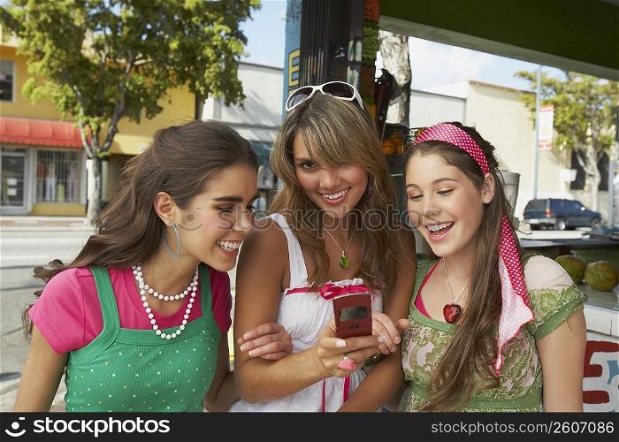 Close-up of a teenage girl holding a mobile phone and smiling with her friends