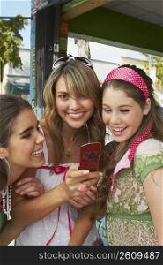 Close-up of a teenage girl holding a mobile phone and smiling with her friends