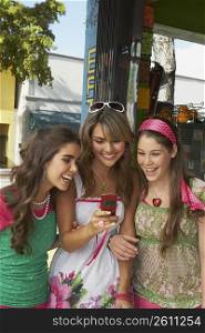 Close-up of a teenage girl holding a mobile phone and standing at the juice bar with her friends