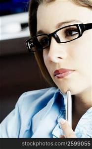 Close-up of a teenage girl holding a pen and thinking