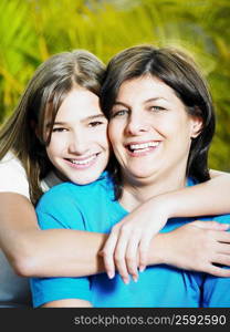 Close-up of a teenage girl hugging her mother from behind