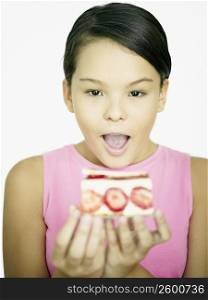 Close-up of a teenage girl looking at a cake in her hands