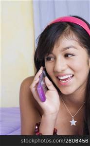 Close-up of a teenage girl lying on the bed and talking on a mobile phone