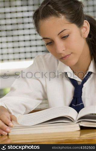 Close-up of a teenage girl reading a textbook