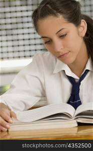 Close-up of a teenage girl reading a textbook