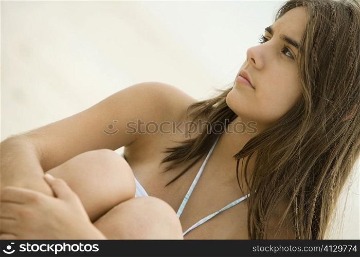Close-up of a teenage girl sitting on the beach smiling