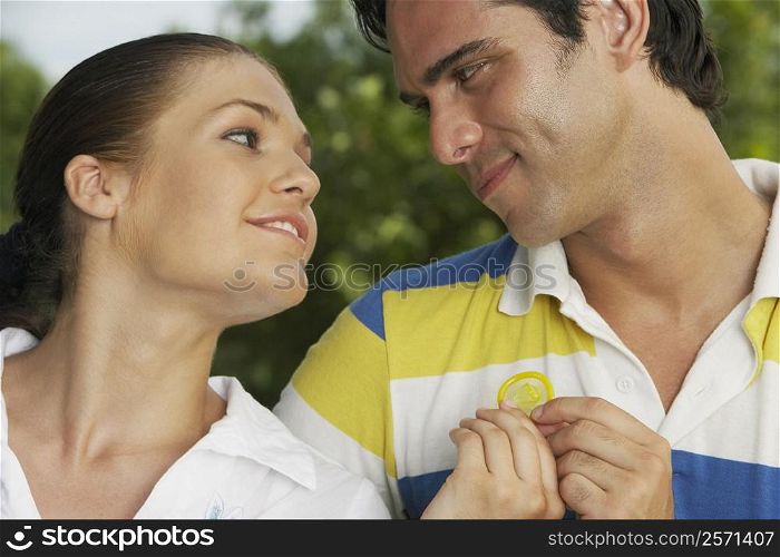Close-up of a teenage girl with a young man holding a condom
