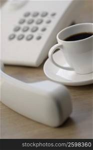 Close-up of a telephone receiver with a cup of tea
