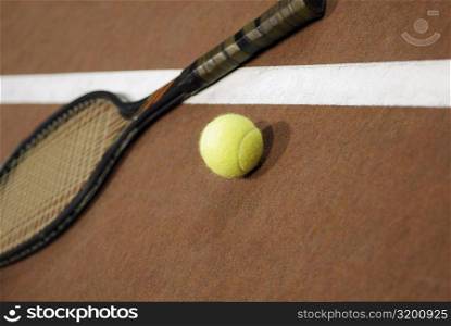 Close-up of a tennis ball with a tennis racket on a tennis court