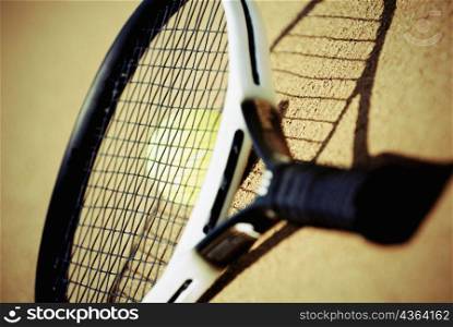 Close-up of a tennis racket over a tennis ball