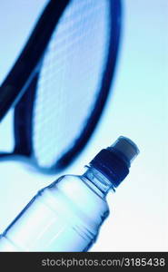 Close-up of a tennis racket with a water bottle