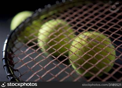 Close-up of a tennis racket with three tennis balls