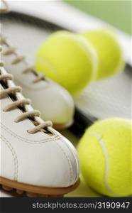 Close-up of a tennis shoe with tennis balls and a racket