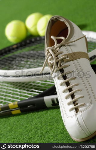 Close-up of a tennis shoe with tennis rackets and tennis balls