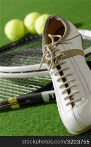 Close-up of a tennis shoe with tennis rackets and tennis balls