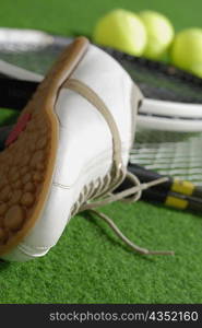 Close-up of a tennis shoe with tennis rackets and tennis balls