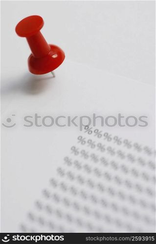 Close-up of a thumbtack on a sheet with percentage signs