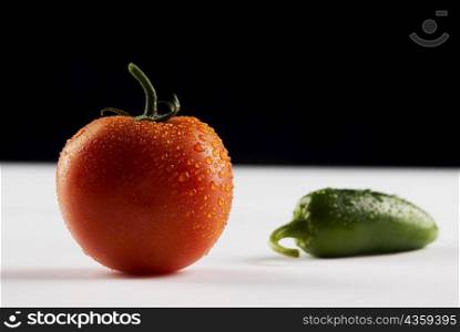 Close-up of a tomato and a green chili pepper