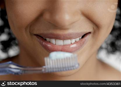 Close-up of a toothbrush with toothpaste in front of a young woman&acute;s mouth