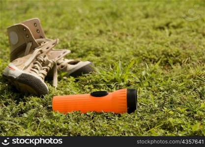 Close-up of a torch light near a pair of shoes lying on the grass