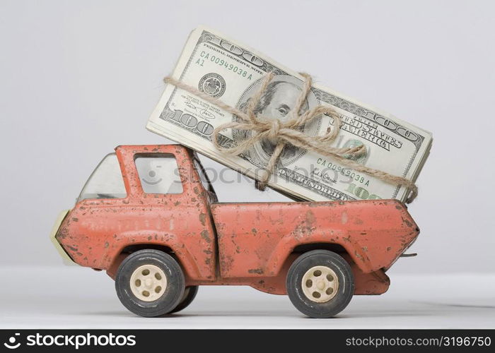 Close-up of a toy truck loading a bundle of paper currency