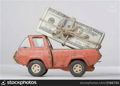 Close-up of a toy truck loading a bundle of paper currency