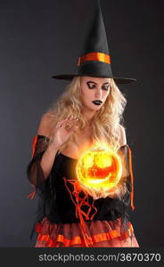 close up of a very sensual cute blond witch in orange and black dress with hat fortune telling with crystall ball