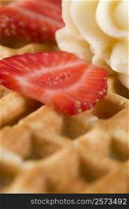 Close-up of a waffle with strawberry slice and whipped cream on it