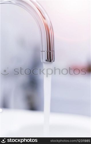 Close up of a water spigot in a clean bathroom. Water saving, sunlight.