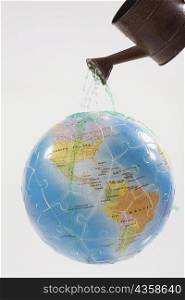 Close-up of a watering can watering on a globe