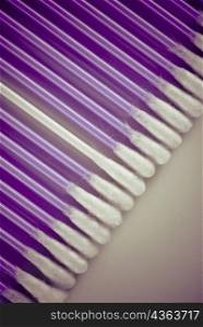 Close-up of a white cotton swab among purple cotton swabs