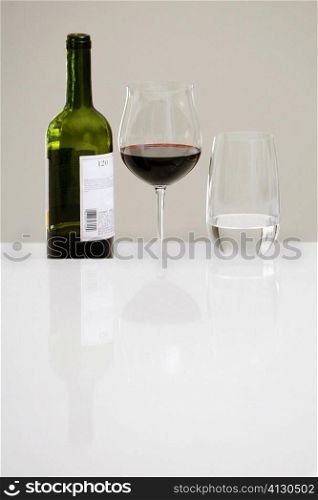 Close-up of a wine bottle with a glass of red wine and a glass of water on a dining table