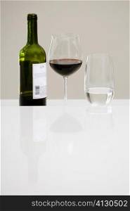 Close-up of a wine bottle with a glass of red wine and a glass of water on a dining table