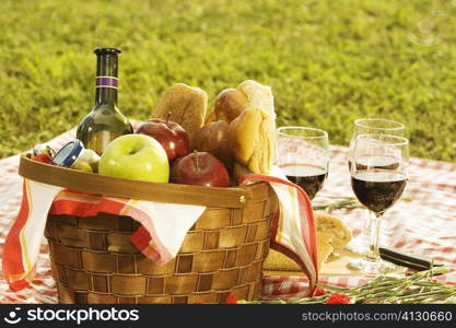 Close-up of a wine bottle with bread and fruits in a picnic basket