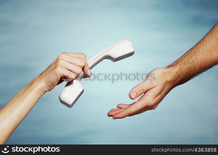 Close-up of a woman&acute;s hand giving a telephone receiver to a man