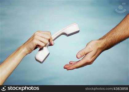 Close-up of a woman&acute;s hand giving a telephone receiver to a man