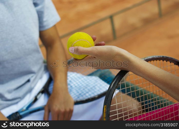 Close-up of a woman&acute;s hand giving a tennis ball to a female tennis player