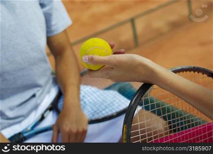 Close-up of a woman&acute;s hand giving a tennis ball to a female tennis player