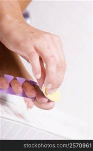 Close-up of a woman&acute;s hand shaping her toenail with a nail file