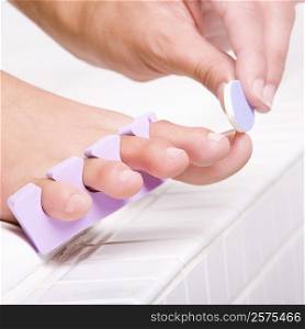 Close-up of a woman&acute;s hand shaping her toenail with a nail file