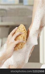 Close-up of a woman&acute;s hand using a bath sponge on her arm