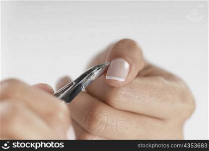 Close-up of a woman&acute;s hand using a nail scissor