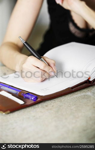Close-up of a woman&acute;s hand writing in a diary