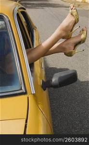 Close-up of a woman&acute;s legs outside the window of a car