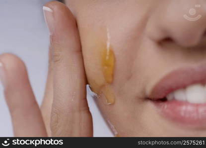 Close-up of a woman applying honey on her cheek