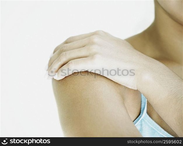 Close-up of a woman applying moisturizer on her shoulder
