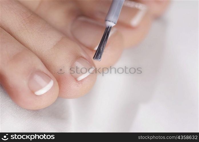 Close-up of a woman applying nail polish on her toes