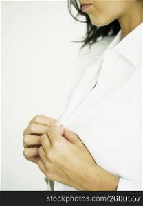 Close-up of a woman buttoning her shirt