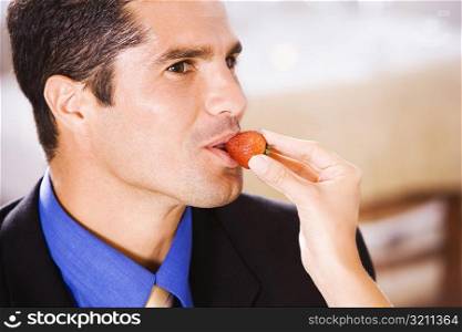 Close-up of a woman feeding a businessman a strawberry